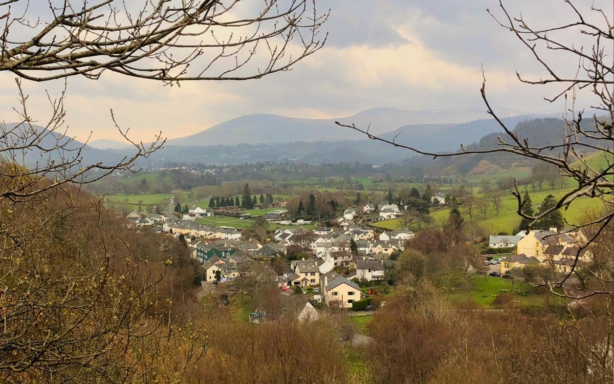 Elevated panoramic landscape view looking down over Braithwaite village houses towards Keswick and the Cumbrian mountains.