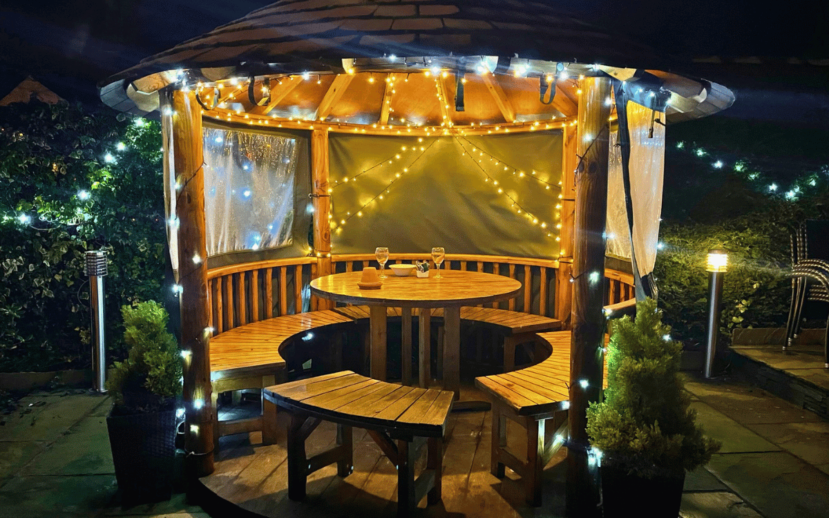 Cosy wooden dining gazebo in The Coledale Inn beer garden lit up with warm fairy lights on an evening in Braithwaite.
