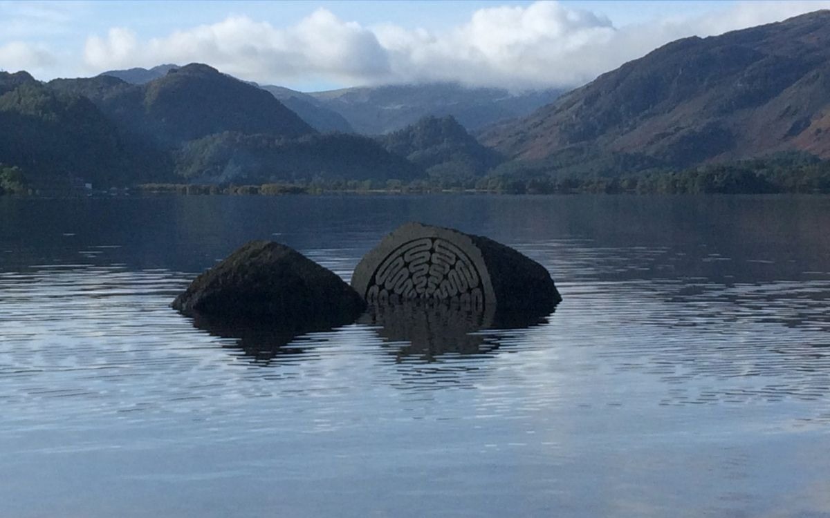 Peter Randall-Page's carved Centenary Stone partially submerged at Calfclose Bay on Derwentwater, looking south towards Castle Crag and Borrowdale.