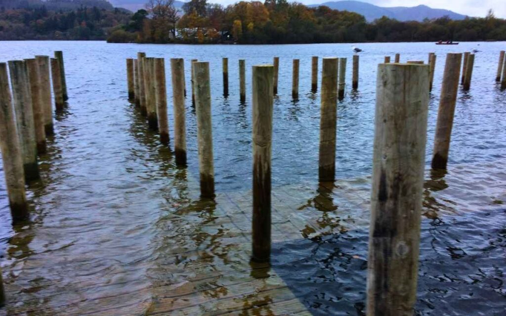 Wooden walkway of the 4th pier at Keswick Launch landings completely submerged beneath the dark high water of Derwent Water.